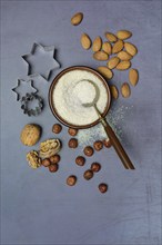 Grated coconut in a bowl and spoon, various nuts and cookie cutters