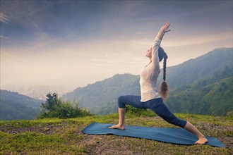 Yoga outdoors, woman doing Ashtanga Vinyasa Yoga asana Virabhadrasana 1 Warrior pose posture in