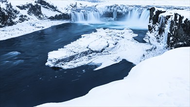 Ice layer in the river Skialfandaljot, behind it the waterfall Godafoss, Northern Iceland Eyestra,