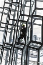 Window cleaners cleaning the glass facade of the Harpa Concert Hall and Congress Centre, interior