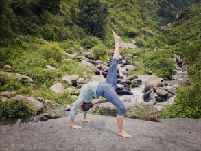 Yoga outdooors, woman doing yoga asana eka pada urdva dhanurasana Upward Bow Pose back benkd