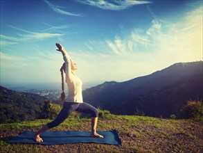 Yoga outdoors, sporty fit woman doing yoga asana Virabhadrasana 1, Warrior pose posture outdoors in