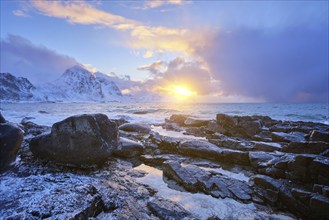 Beach of Norwegian sea on rocky coast in fjord on sunset in winter. Vareid beach, Lofoten islands,