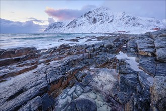 Beach of Norwegian sea on rocky coast in fjord on sunset in winter. Vareid beach, Lofoten islands,