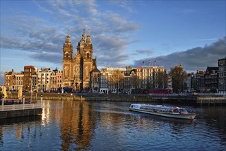 AMSTERDAM, NETHERLANDS, MAY 9, 2017: Tourist boat in Amsterdam canal and Church of Saint Nicholas