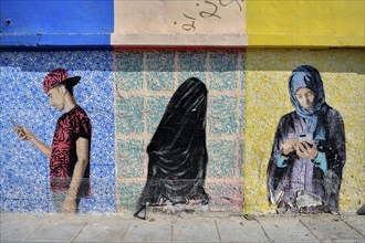 Mural of two veiled woman and a young man with a mobile phone, graffito, Al Khobar, ash-Sharqiyya