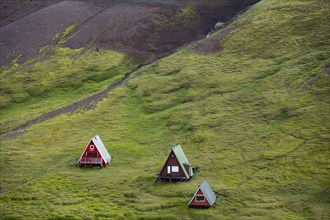 Cabins among volcanic landscape with black sand and green grass, Ásgarður, Kerlingarfjöll,