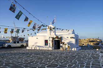 White Cycladic Greek Orthodox Church of Agios Nikolaos, decorated with flags, harbour of Naoussa,