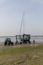 Tractor launching boat in cradle, River Blackwater estuary, West Mersea, Mersea Island, Essex,