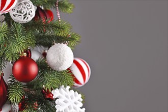 Christmas tree with white and red ornament baubles in front of gray background