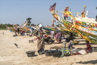 The fishermen's wives with the colourful fishing boats on the beach of Sanyang, Gambia, West