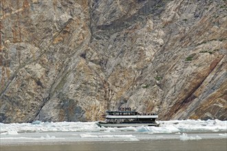 Small boat between ice of a glacier calving into the sea, Tracy Arm Fiord, Tongass National Forest,