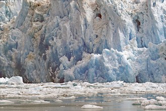 Ice of a glacier calving into the sea shimmers bluish, Tracy Arm Fiord, Tongass National Forest,