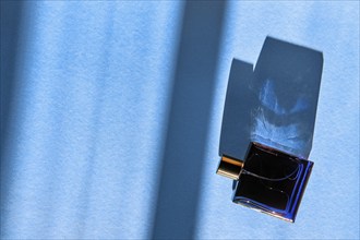 Bottle of perfume for men on blue background under sun light from the window