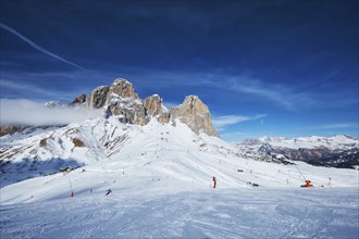 View of a ski resort piste with people skiing in Dolomites in Italy