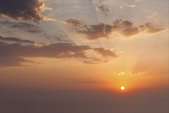 Evening sunset sky with sun and dramatic clouds