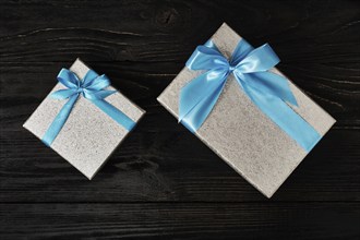 Gift birthday Christmas present concept, silver gift box with blue ribbon on dark wooden background