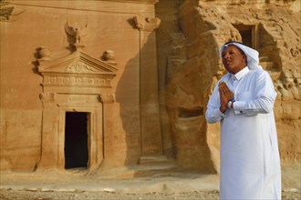 Rawi, storyteller, in front of the Nabataean tombs at the rock Qasr Al-Bint, Hegra or Madain Salih,