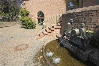 Ornamental fountain with two figures, wheelbarrows loaded with barrels and local history museum in