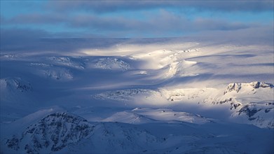 Light and shadow over the snowy hills and mountains of Myrdalsjökull, Sudurland, Iceland, Europe