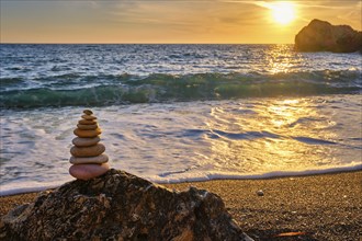 Cairn stack of stones pebbles cairn on the beach coast of the seaon sunset. Agios Ioannis beach,