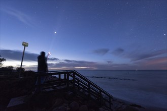 Person shines torch into the starry sky, Baltic Sea island of Mon, Denmark, Europe