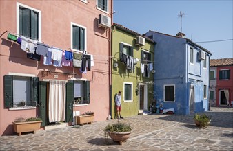 Young man leaning against a house wall, colourful houses with flowers, colourful house facades,