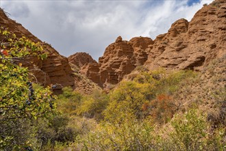 Eroded mountain landscape with sandstone cliffs, canyon with red and orange rock formations,