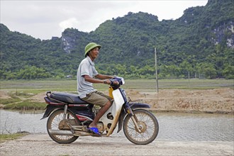 Happy Vietnamese man riding Honda Dream II motorcycle, motorbike in the countryside, Ninh Bình