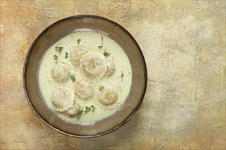 Ravioli in cream sauce, spices and herbs, top view, no people