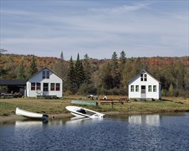 Small country chalets with boats on lake shoreline in autumn, Chertsey, Lanaudiere, Quebec, Canada,