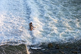 Girl bathing in the spray of the Lech weir, jumping into the white foaming water of the cascades,