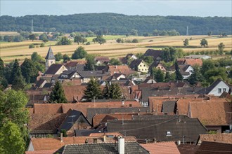 View of a picturesque village with red roofs and a church, surrounded by fields and trees, Alsace,