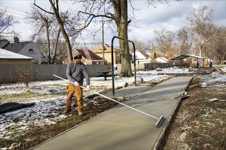 Detroit, Michigan - Workers pour and finish concrete for walking paths in Three Mile Park in