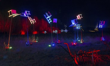 Colourful chairs on poles in the night landscape with wagon wheels in the foreground, world of