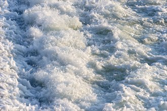 Agitated white foaming water, spray on cascades at the Lech weir, river Lech, background, Landsberg