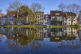 Historic houses, bare trees, symmetrical reflections on the water surface, River Trave, Old Town,