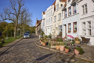 Street An der Obertrave with historic buildings, cobblestone pavement, bare trees, flower pots with