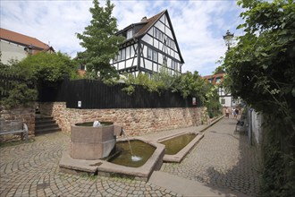 Red fountain with alley and half-timbered house, Seligenstadt, Main, Hesse, Germany, Europe