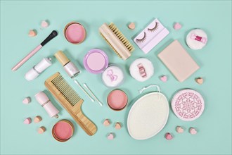 Pink makeup beauty products like brushes, powder or lipstick on teal blue background