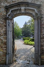 Brugge street architecture: arch on cobblestone path and old houses in Bruges, Belgium, Europe