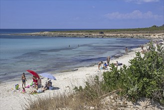 Italian tourists swimming and sunbathing on sandy beach in summer along the Ionian Sea in the