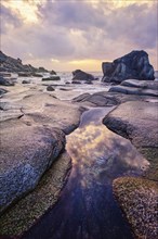 Rocks on beach of fjord of Norwegian sea in winteron sunset. Utakliev beach, Lofoten islands,