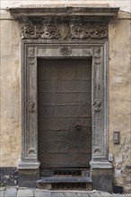 Historic entrance door with decorative floral reliefs on the frame in the historic city centre,