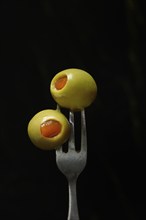 Green olives on fork, stuffed with pieces of paprika