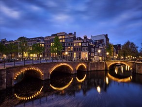 Night view of Amterdam cityscape with canal, bridge and medieval houses in the evening twilight