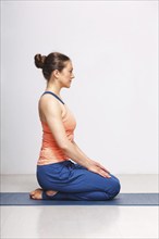 Woman in Hatha yoga asana Vajrasana, vajra pose or diamond pose on yoga mat on yoga mat in studio