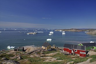 Simple, colourful houses on the edge of a bay covered with icebergs, Ilulissat, Arctic, Disko Bay,