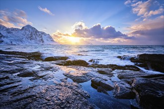 Beach of Norwegian sea on rocky coast in fjord on sunset in winter. Vareid beach, Lofoten islands,