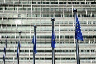 Helplessly drooping EU European Union flags with the European Comission building in Background.